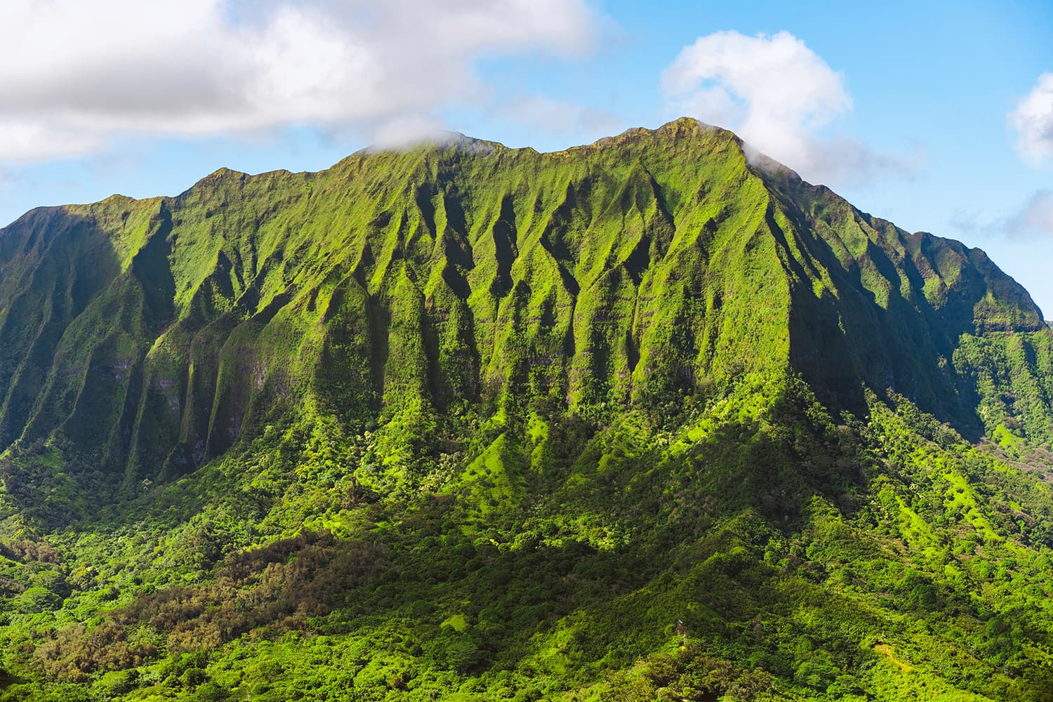 Steep green ridgeline of the Waianae Mountains on Oahu with clouds at the peak