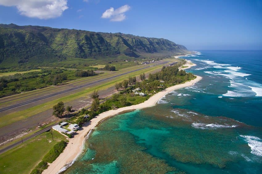 Aerial view of Mokuleia Beach and Dillingham Airfield on Oahu's North Shore with turquoise reef waters