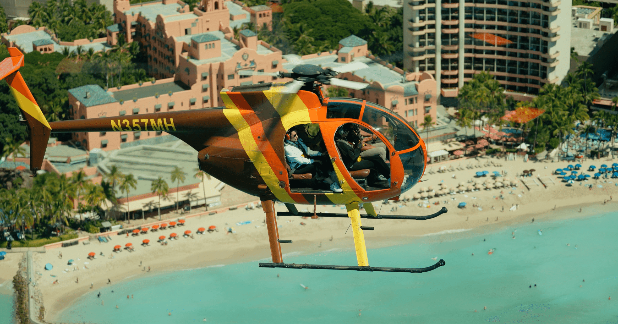 Doors-off helicopter flying over Waikiki Beach with the Royal Hawaiian hotel below